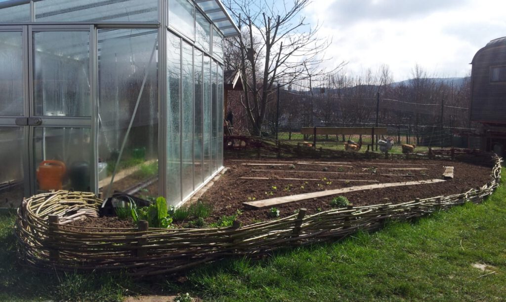 Gewächshaus mit Weidezaun im Bio-Gemüsegarten